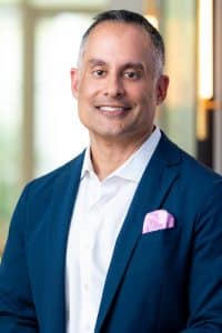 Dr. Sam Jejurikar smiling in a navy suit, honored as one of D Magazine's Best Doctors of 2023.
